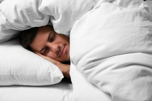 man sleeping under soft blanket in bed at home